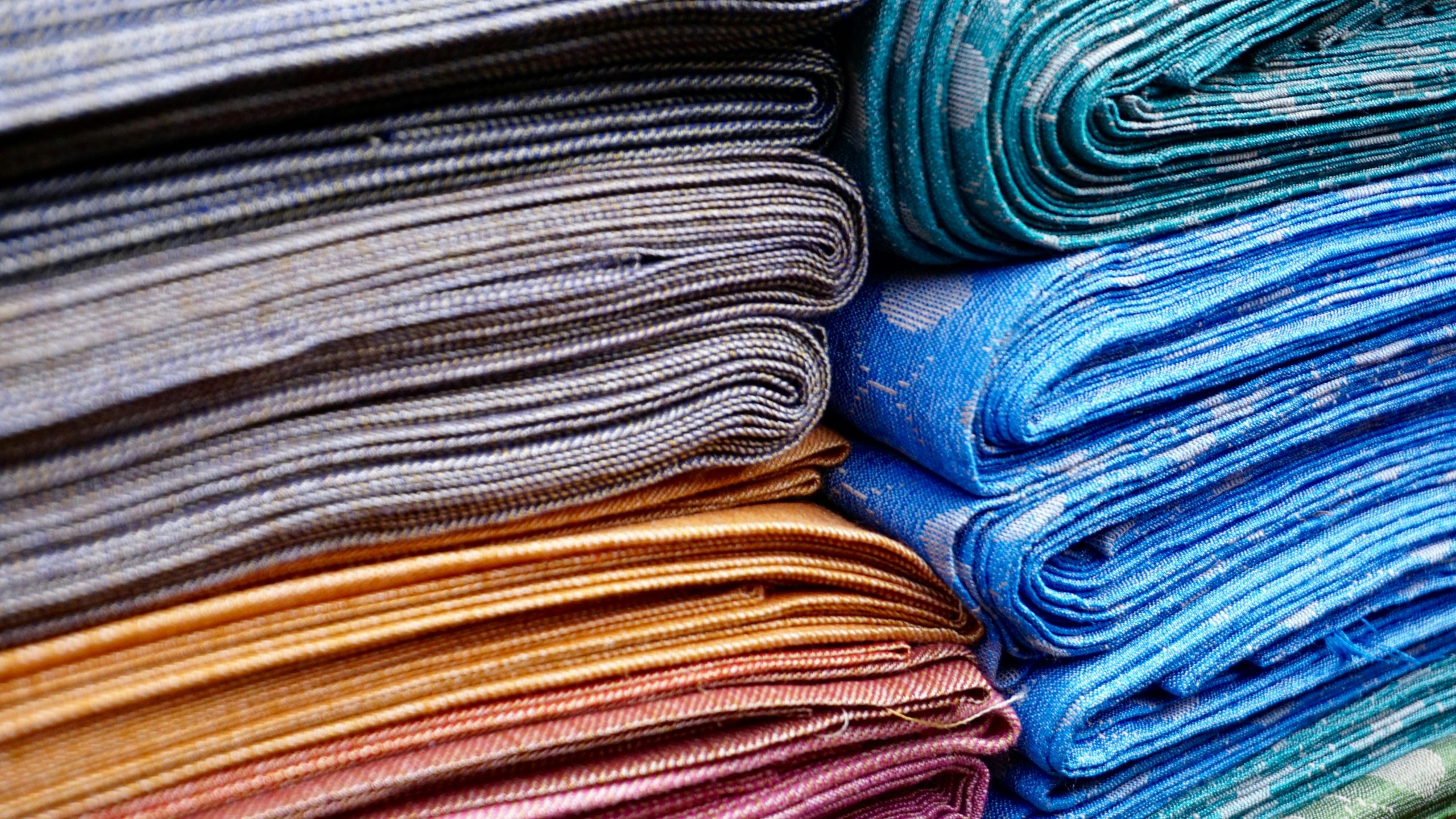 Vibrant stacked textiles displaying intricate and colorful woven patterns.